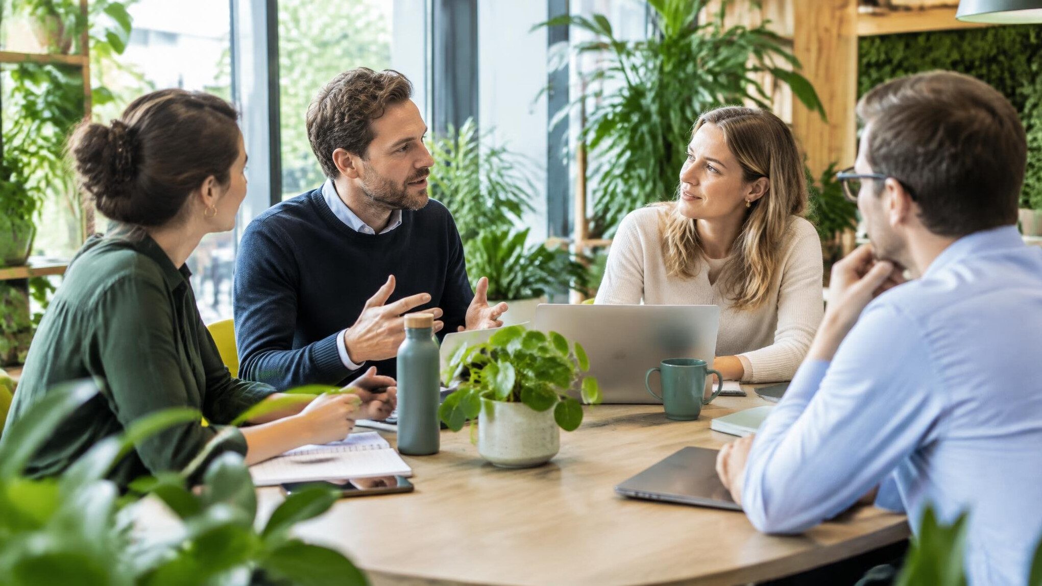 Business meeting in a green office surrounded by plants discussing sustainability
